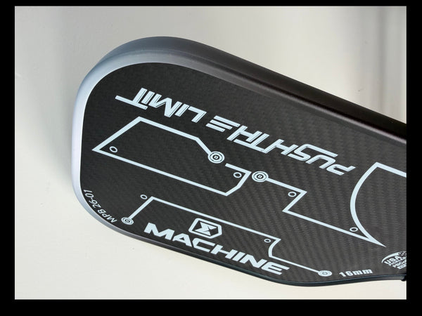 Close-up of a black and silver golf club head with branding on a light gray background